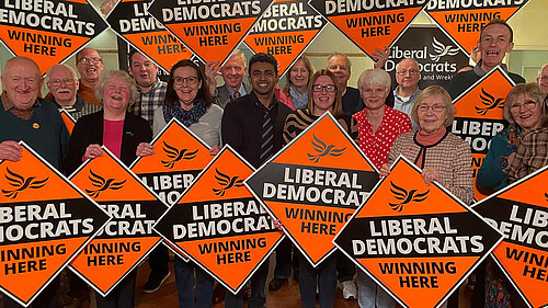 Liberal Democrat activists holding signs saying "Liberal Democrats Winning Here"